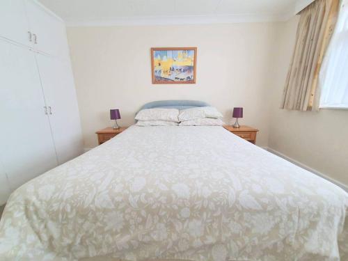 a white bed in a bedroom with two lamps at Wentworth Apartment with 2 bedrooms, Superfast Wi-Fi and Parking in Sittingbourne