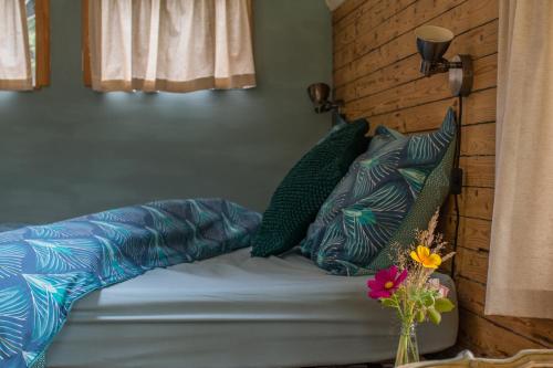 a bedroom with a bed with blue and green pillows at La Roulotte de la Ferme de Froidefontaine in Havelange