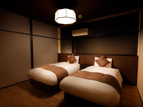 een slaapkamer met 2 bedden in een kamer met een licht bij Connect inn Gion-Bishamoncho in Kyoto