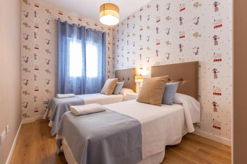 a bedroom with two beds and a wall with wallpaper at Apartamento Sofia Ronda Center in Ronda