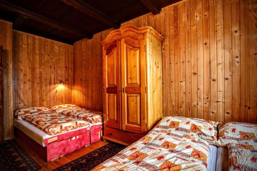 a bedroom with two beds and a wooden wall at Horská chata Kouty in Loučná nad Desnou