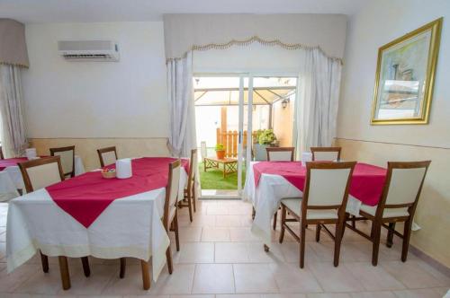 a dining room with two tables and chairs with pink tablecloths at AIR La Casa di Gio' in Isola Rossa