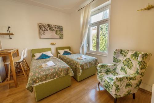 a room with two beds and a chair and a window at Apartments Villa Devana 2 in Opatija