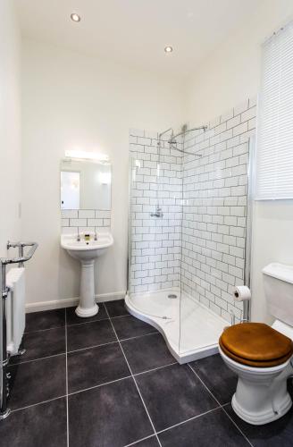 a bathroom with a shower and a toilet and a sink at Tailor Room 1 in Lincoln