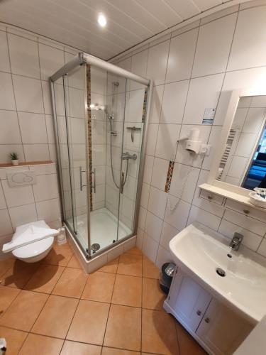 a bathroom with a shower and a toilet and a sink at Hotel Pension Loose in Borkum
