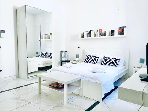 Dormitorio blanco con cama y mesa en U Palazzieddu Rooms, en Pachino