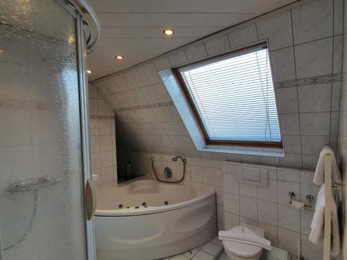 a bathroom with a tub and a toilet and a window at Hotel Pension Loose in Borkum