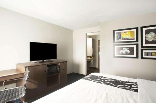 a bedroom with a bed and a flat screen tv at La Quinta Inn by Wyndham St. Louis Hazelwood - Airport North in Hazelwood