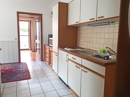 eine Küche mit weißen Schränken und Fliesenboden in der Unterkunft Ferienwohnung Schwinghammer in Aschau im Chiemgau