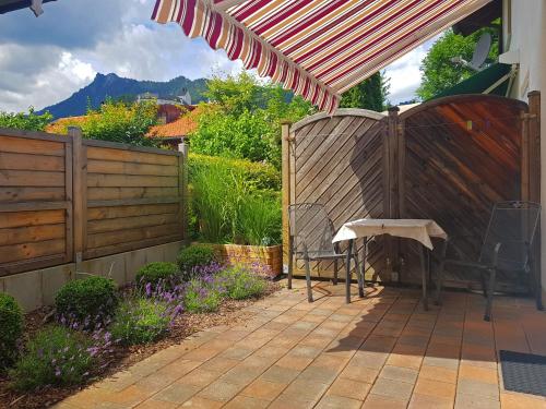 Un patio con una silla bajo una sombrilla y una valla. en Ferienwohnung Schwinghammer, en Aschau im Chiemgau
