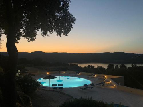 a large swimming pool with a sunset in the background at Hotel Valkarana Country Relais in Sant Antonio Di Gallura