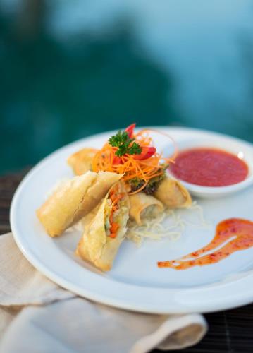 a white plate with a sandwich and a bowl of soup at Mimpi Resort Tulamben in Tulamben