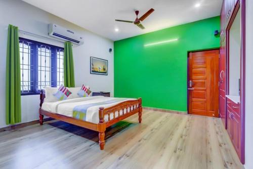 a green bedroom with a bed and a wooden door at Paradise Home Stay Pondicherry Luxury Stay with Private Swimming Pool in Auroville