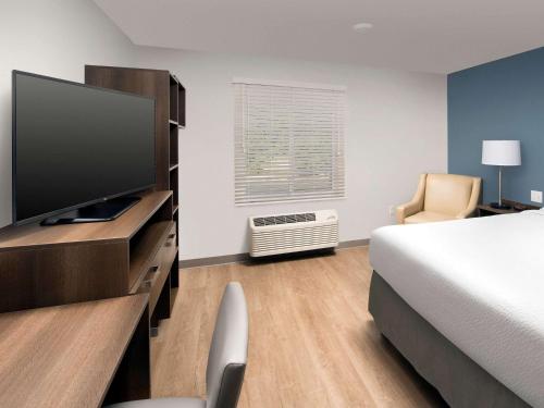 a hotel room with a bed and a flat screen tv at WoodSpring Suites Toledo Maumee in Maumee