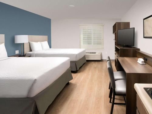 a hotel room with two beds and a desk at WoodSpring Suites Toledo Maumee in Maumee
