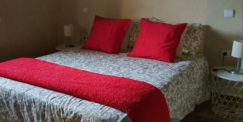 a bed with red pillows and a red blanket at casa Rural Las Traviesas in Candeleda