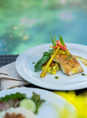 a white plate with a piece of fish and noodles at Mimpi Resort Tulamben in Tulamben