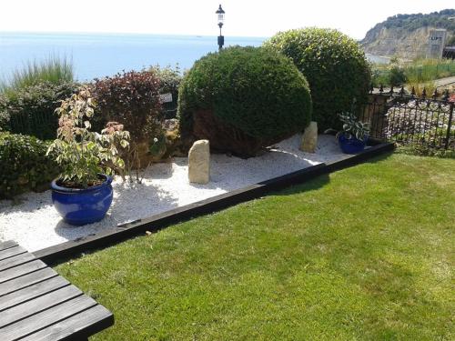 um jardim com um banco e alguns arbustos e o oceano em The Cliff Hall em Shanklin