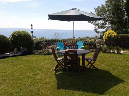 a table and chairs with an umbrella in a yard at The Cliff Hall in Shanklin