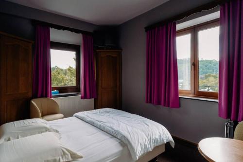 een slaapkamer met een bed en 2 ramen bij Les Genêts in La-Roche-en-Ardenne