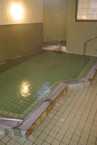 a swimming pool with green water in a room at Daikokuya Ryokan in Hakodate