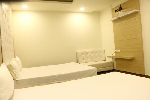 a small room with two beds and a chair at lords residency in Bhopal