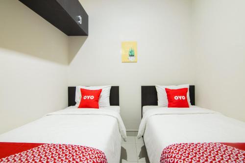 two twin beds in a room with red pillows at OYO 3826 Columbus Residence K11 in Karawang