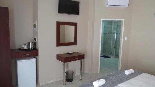 Un dormitorio con una cama, un lavabo y un espejo. en Villa Strada Guesthouse, en Klerksdorp