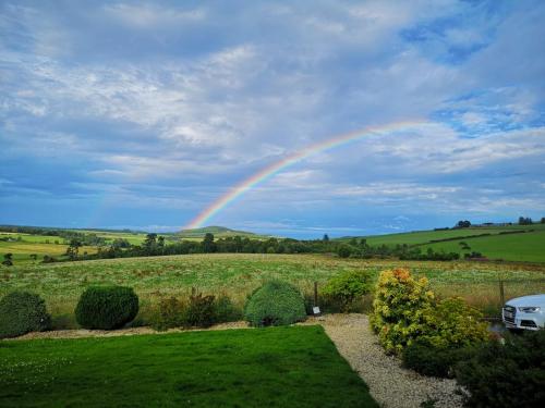 een regenboog in de lucht boven een veld bij Hillhaven Bed &Breakfast in Fortrose