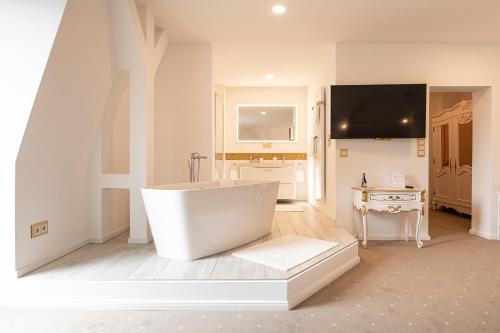 a large white bathroom with a tub and a television at Schloss Breitenfeld Hotel & Tagung in Leipzig