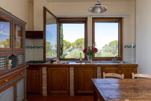 a kitchen with two windows and a table with chairs at Relais Riserva di Fizzano in Castellina in Chianti