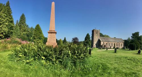a monument in the middle of a field next to a building at Kings Head - Riverside, Ravenstonedale in Ravenstonedale