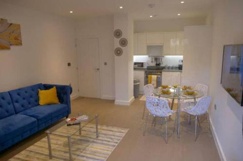 a living room with a blue couch and a table and chairs at Maplewood properties - St Albans one bedroom luxurious flat in St. Albans