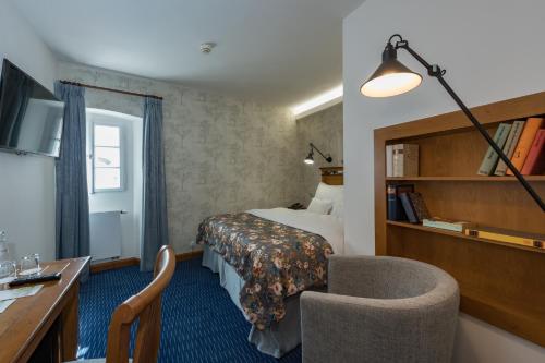a hotel room with a bed and a desk and a chair at Monastery Garden Prague in Prague