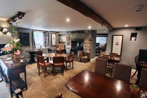 a dining room with tables and chairs and a fireplace at Kings Head - Riverside, Ravenstonedale in Ravenstonedale