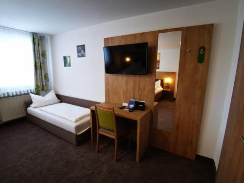 a hotel room with a desk and a bed and a television at Gasthof Endres in Allersberg