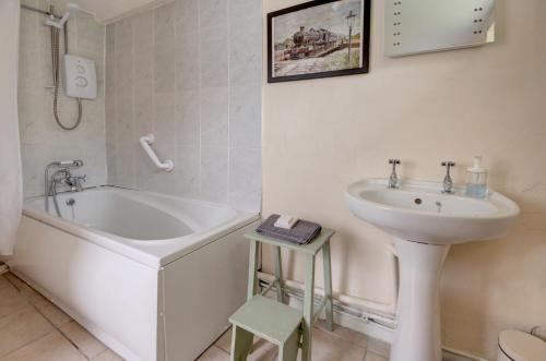 un bagno bianco con lavandino, vasca e lavandino di The Courtyard Cirencester a Cirencester