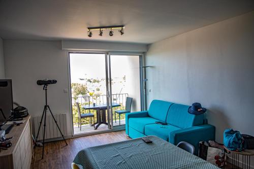 d'un salon avec un canapé bleu et d'un balcon. dans l'établissement Appartement vue panoramique mer, prêt de vélos, WIFI, à Quiberon