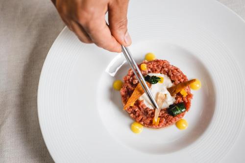 a person eating a plate of food with a fork and knife at Relais Riserva di Fizzano in Castellina in Chianti