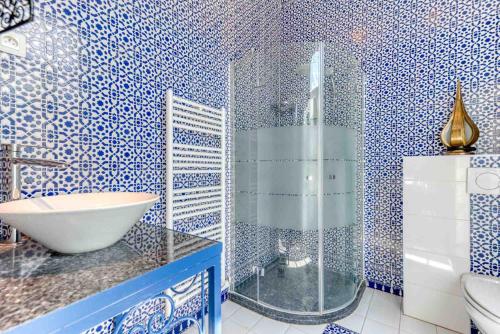 a blue and white bathroom with a sink and a shower at Ryad Mogador Liège in Liège