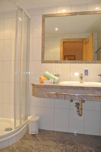 a bathroom with a shower and a sink and a mirror at Hotel Garni Central - Zimmer - Studios - Apartments in Kappl