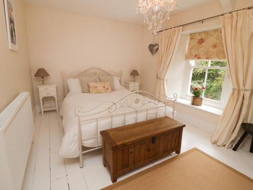 a bedroom with a white bed and a window at Fairfield Cottage in Boscastle
