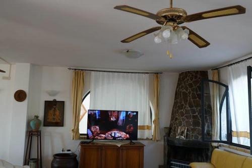 a living room with a ceiling fan and a tv at Villa Grazia in Capo Vaticano