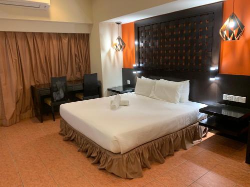 una camera da letto con un grande letto bianco con testiera nera di Resort Suites by Landmark at Bandar Sunway Sunway Lagoon a Kampong Penaga