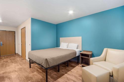 a bedroom with a bed and a couch and a chair at WoodSpring Suites | North Charleston Airport I-526 in Charleston