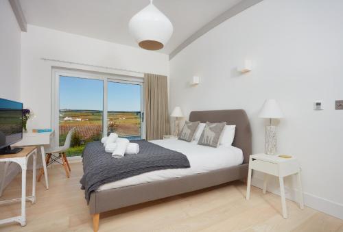 a bedroom with a bed and a desk and a window at Sundown in Bude