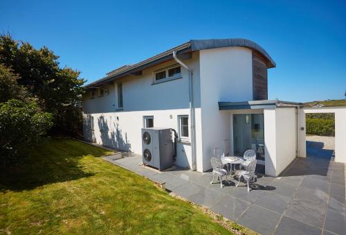 a white house with a patio and a table and chairs at Sundown in Bude