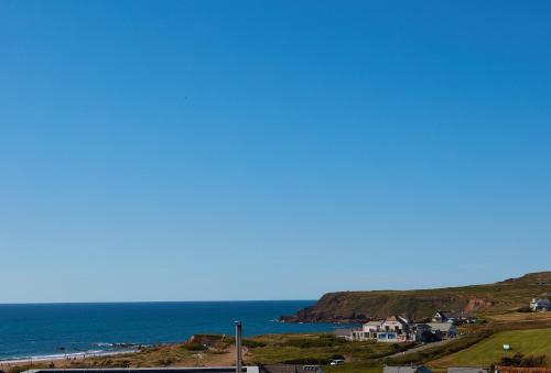 a view of the ocean and a beach with houses at Sundown in Bude