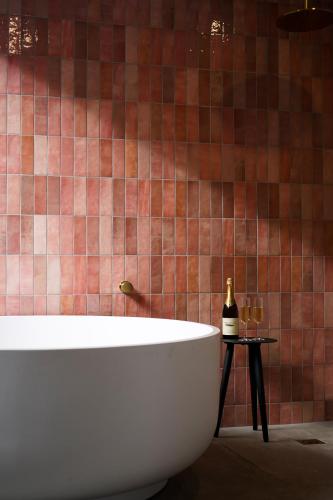 a bathroom with a tub and a tiled wall at Melo Studios in Dunsborough