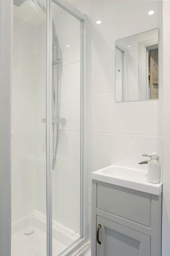 a white bathroom with a shower and a sink at Hastings Retreat Rural barn conversions with Private Lake in Ashby de la Zouch